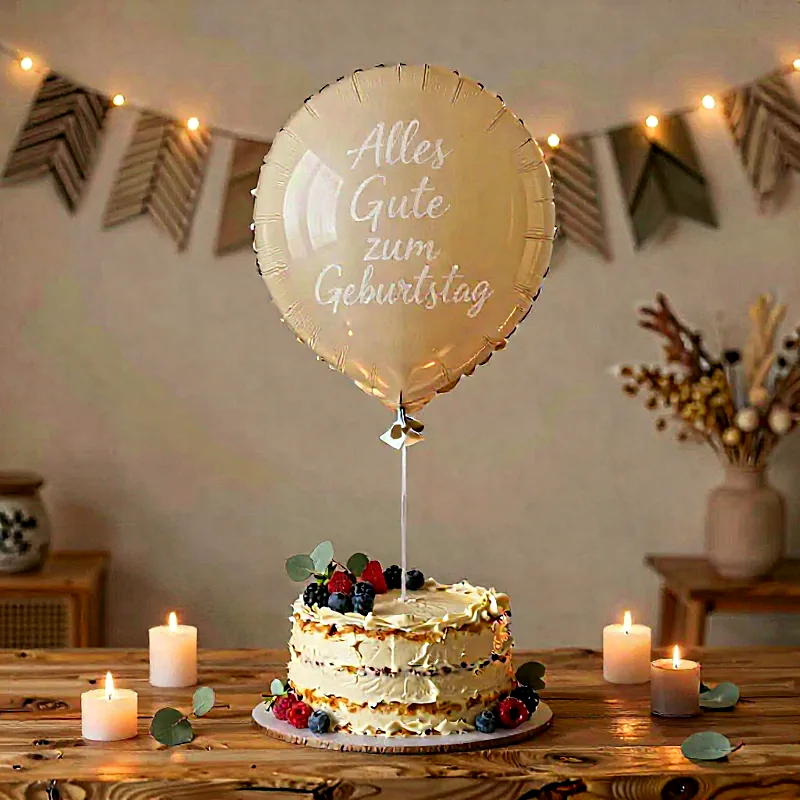 Festliches Geburtstagsarrangement auf einem Holztisch mit einer cremfarbenen Torte, dekoriert mit frischen Beeren und Eukalyptus. Ein goldener Ballon schwebt darüber, daneben strahlen warme Kerzenlichter.