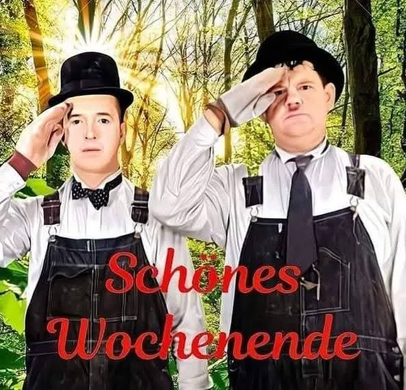 Zwei Männer im Stil von Laurel und Hardy, mit Latzhosen und Hüten, salutieren ernsthaft vor einem hellen, sonnendurchfluteten Wald. Der rote Schriftzug "Schönes Wochenende" schwebt im Vordergrund.