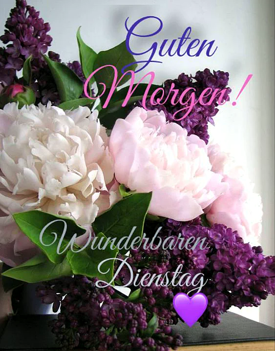 Ein üppiger Blumenstrauß aus hellrosa Pfingstrosen und dunkellila Fliederzweigen in einer Vase, darüber schweben die Worte „Guten Morgen!“ und „Wunderbaren Dienstag“ mit einem lila Herz, vermittelt eine frische, frühlingshafte und ruhige Stimmung.