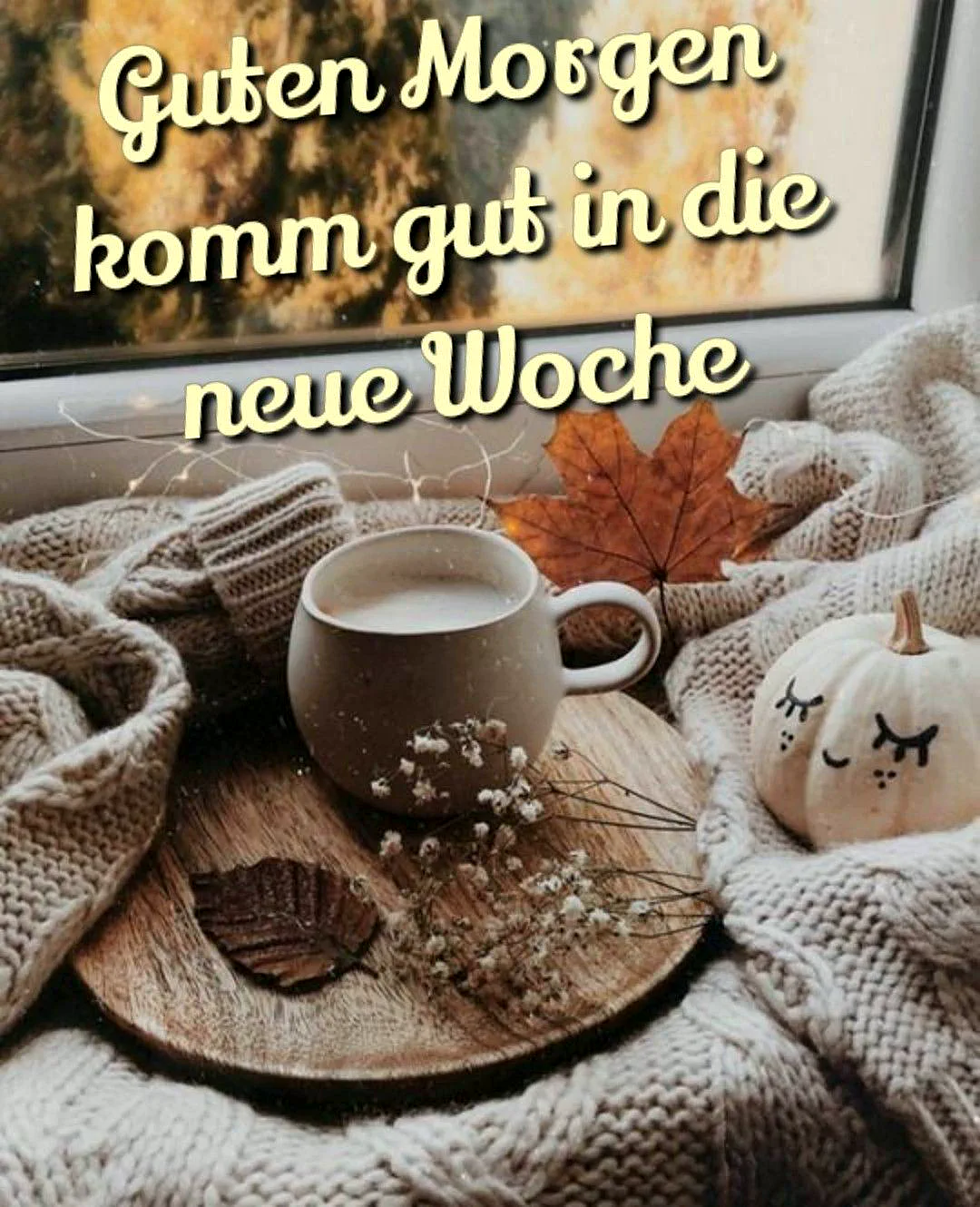 Ein herbstliches Stillleben mit einer Tasse Kaffee auf einem Holzteller, umgeben von einem Pullover, einem Kürbis, Blättern und Blumen auf einer Fensterbank.