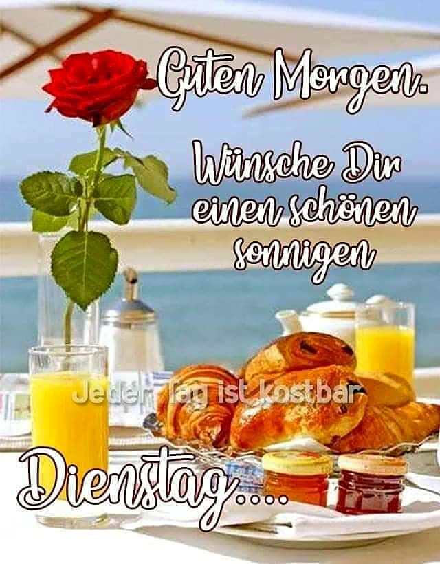 Ein sonniger Frühstückstisch mit einer roten Rose in einer Vase, Croissants, Marmelade und Orangensaft, im Hintergrund ein Meerblick
