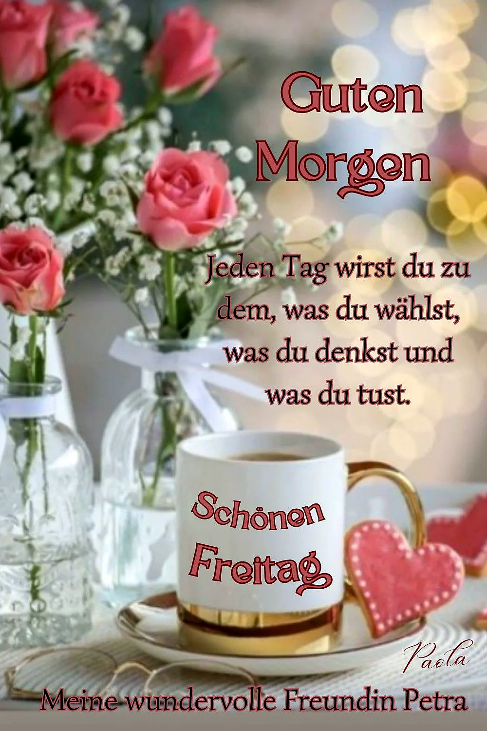 Ein weißer Kaffeebecher mit der Aufschrift 'Schönen Freitag' auf einer goldenen Untertasse, daneben ein rosa Herzgebäck und eine Vase mit rosa Rosen und Baby's Breath Blumen, im Hintergrund unscharfe Lichter.