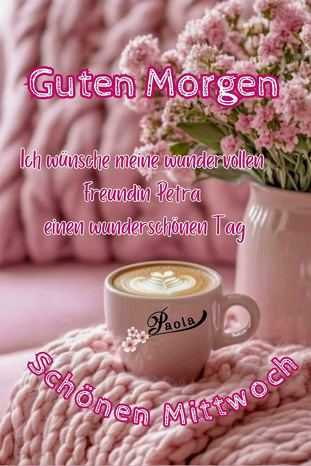 Ein rosa Kaffee-Becher mit einem Herz-Muster auf dem Kaffee, umgeben von rosa Blumen und einem rosa Sofa im Hintergrund.