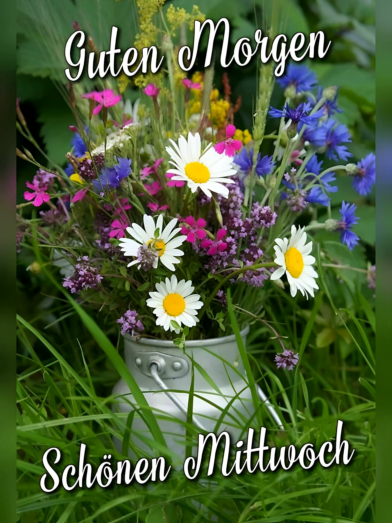 Ein bunter Blumenstrauß in einer Metallschale, bestehend aus weißen Margeriten, rosa, gelben und blauen Blumen, umgeben von grünem Gras.
