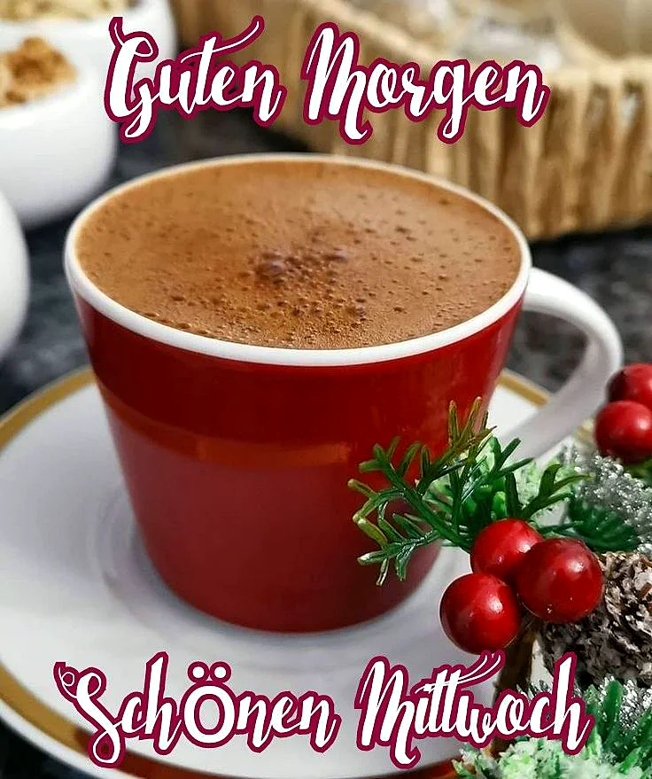 Ein roter Kaffeebecher auf einer weißen Untertasse mit goldenen Rand, gefüllt mit einer cremigen Kaffee Oberfläche, daneben ein paar rote Beeren und grüne Blätter, im Hintergrund ein Korb und ein weißer Teller