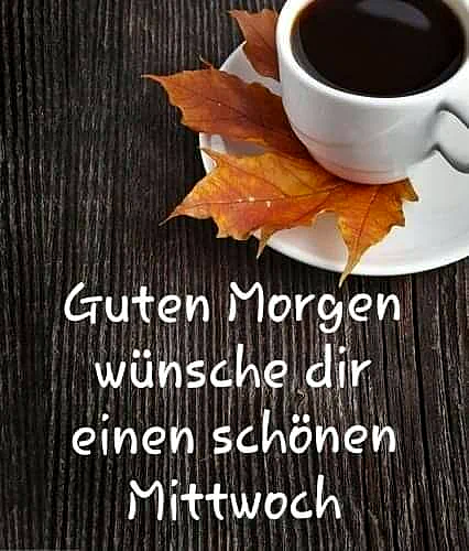 Ein weißer Kaffeebecher auf einer Untertasse mit Herbstlaub liegt auf einem dunklen Holztisch, daneben der Gruß Guten Morgen wünsche dir einen schönen Mittwoch.