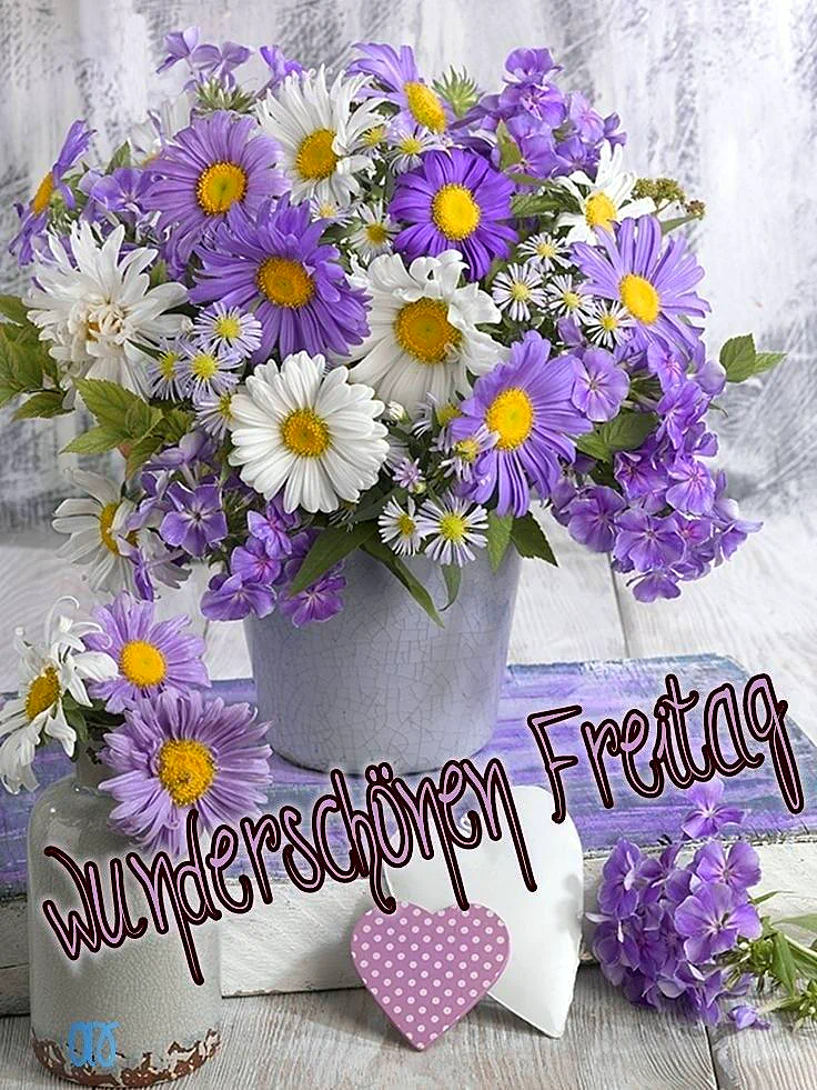 Ein Strauß violetter und weißer Blumen in einem hellen Topf auf einem rustikalen Holztisch, daneben ein kleines Herz aus Stoff mit weißen Punkten auf violettem Grund.