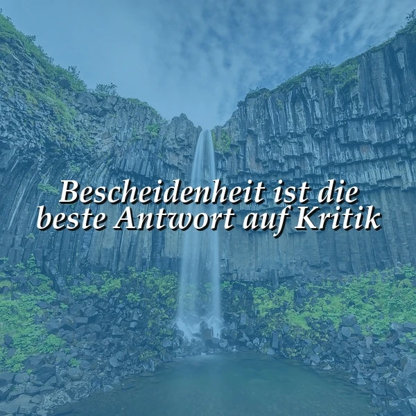 Ein majestätischer Wasserfall stürzt über dunkle Basaltsäulen, umgeben von grüner Natur unter leicht bewölktem Himmel. In weißer Schrift steht zentral: "Bescheidenheit ist die beste Antwort auf Kritik".