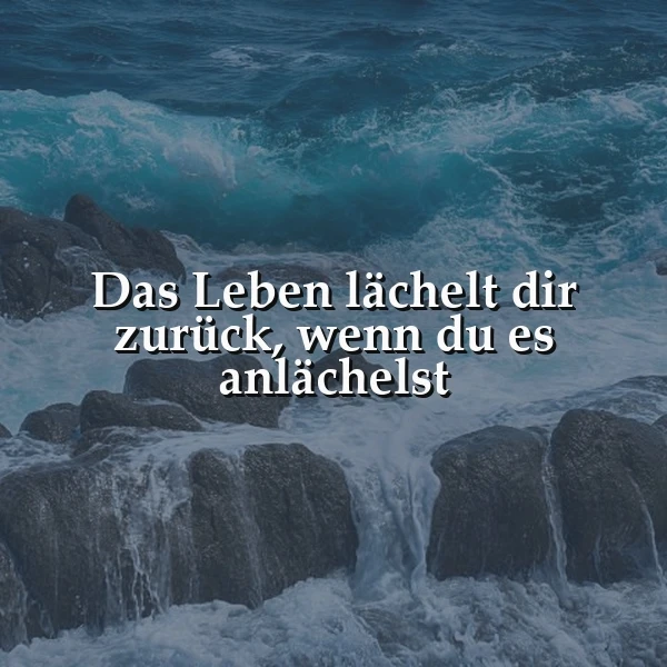 Ein inspirierendes Bild mit dem Zitat: Das Leben lächelt dir zurück, wenn du es anlächelst. Kräftige blaue Wellen schlagen auf dunkle Felsen. Die Szene vermittelt eine dynamische, doch optimistische Meeresstimmung.