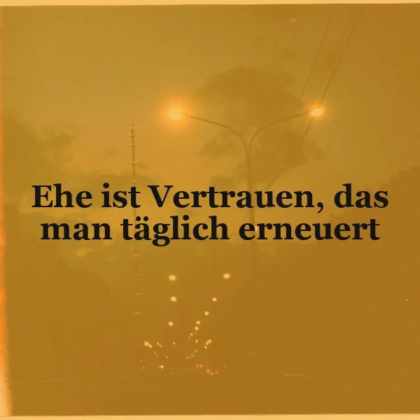 Ein gelbes Bild mit einer Straßenlaterne, die durch einen nebligen Abendhimmel scheint, und dem Zitat 'Ehe ist Vertrauen, das man täglich erneuert' in schwarzer Schrift