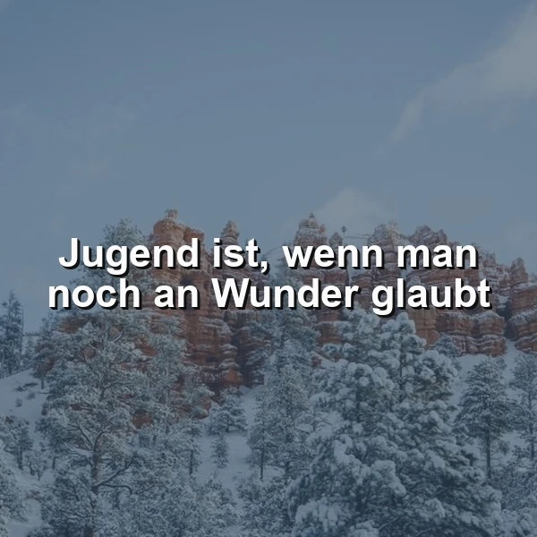 Ein winterliches Bergpanorama mit schneebedeckten Bäumen und rötlichen Felsformationen unter bewölktem Himmel. Der weiße Spruch "Jugend ist, wenn man noch an Wunder glaubt" liegt friedlich über der Szenerie und inspiriert zur Hoffnung.