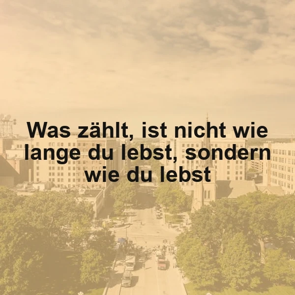 Ein inspirierendes Zitat über die Lebensqualität, 'Was zählt, ist nicht wie lange du lebst, sondern wie du lebst', vor einer beruhigenden Ansicht einer Stadt mit Gebäuden und grünen Bäumen unter einem bewölkten Himmel.