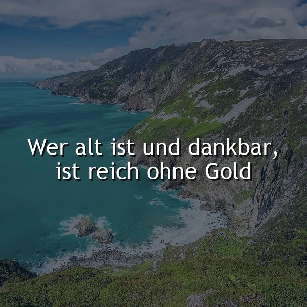 Ein Panorama-Foto einer Küstenlandschaft mit steilen, grünen Hügeln, die zum tiefblauen Meer hin abfallen. Der Himmel ist teilweise bewölkt. Das Bild zeigt ein Zitat: 'Wer alt ist und dankbar, ist reich ohne Gold'.