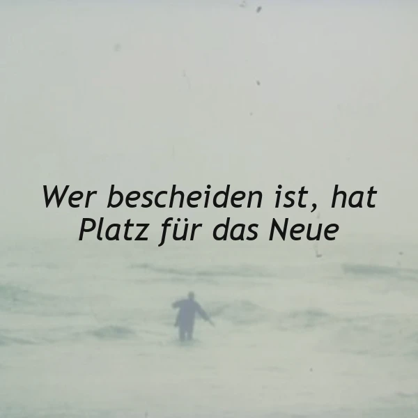 Ein Mensch steht allein am Strand, umgeben von Wellen, im Hintergrund ein nebeliger Himmel, das Zitat 'Wer bescheiden ist, hat Platz für das Neue' ist prominent platziert