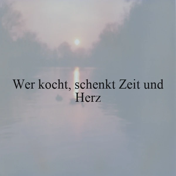 Ein stimmungsvolles Bild zeigt einen zarten Sonnenaufgang über einem nebelverhangenen See. Sanfte Pastelltöne und das Licht auf dem Wasser prägen die Atmosphäre. Zentral steht der Spruch "Wer kocht, schenkt Zeit und Herz", der Geborgenheit und Liebe vermittelt.