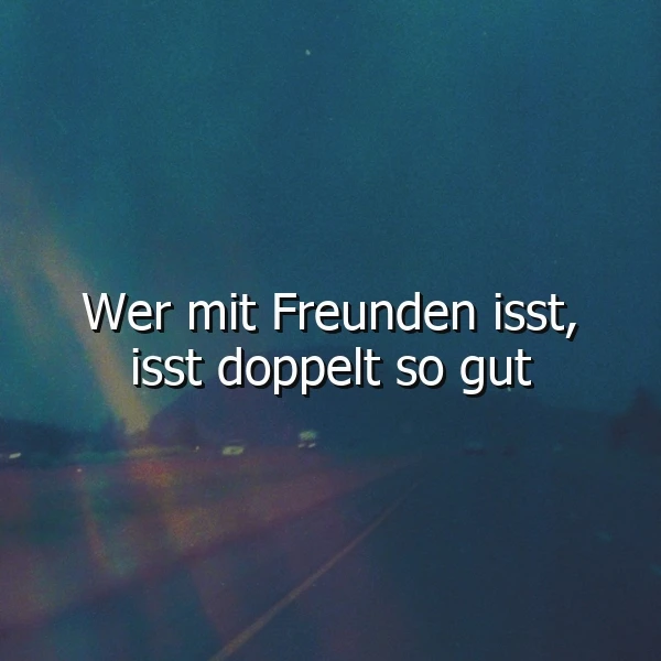 Abstrakter, dunkler Hintergrund mit verschwommenen Straßenlichtern und farbigen Streifen, darauf der weiße Spruch: Wer mit Freunden isst, isst doppelt so gut. Die Szene vermittelt eine ruhige und nachdenkliche Atmosphäre der Verbundenheit.
